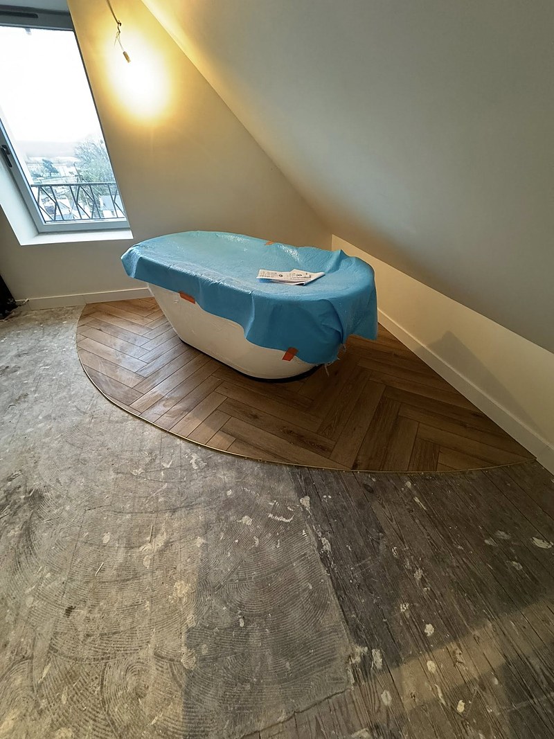 Sol vinyle étanche posé en bâton rompu avec baguette laiton autour d'une baignoire, à Quimper.